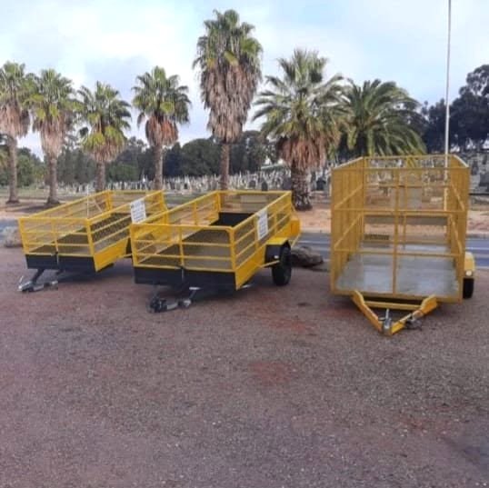 Three yellow AAA trailers: two open drop-side trailers and a high mesh cage trailer